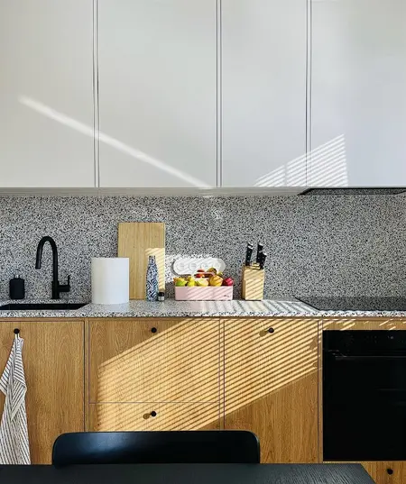Kuchnia minimalistyczna z drewnianymi meblami i owocami na blacie.