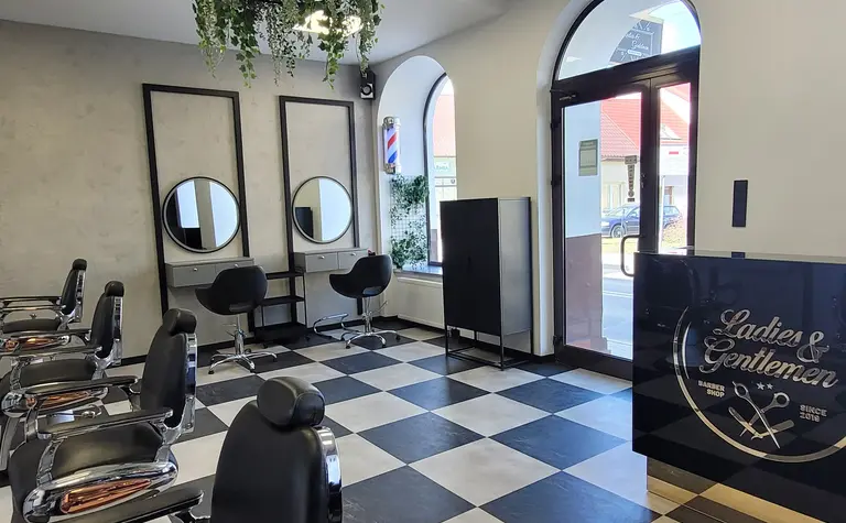 Wnętrze salonu fryzjerskiego z czarnymi fotelami i roślinami w stylu industrialnym i nowoczesnym.