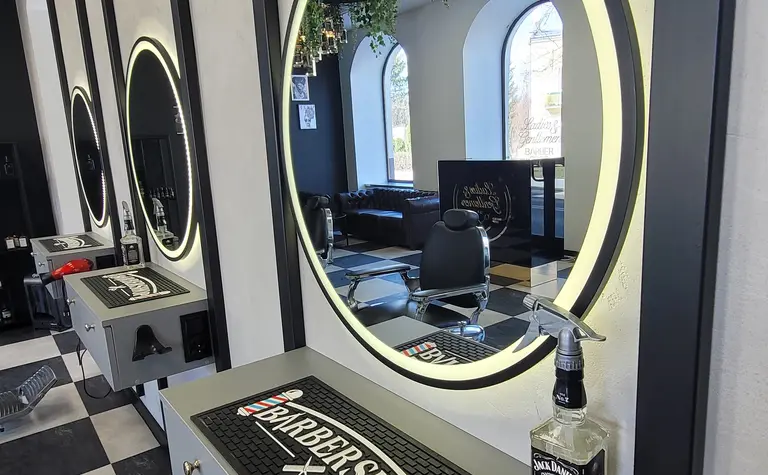 Wnętrze barber shopu z lustrami, roślinami i nowoczesnym wyposażeniem.