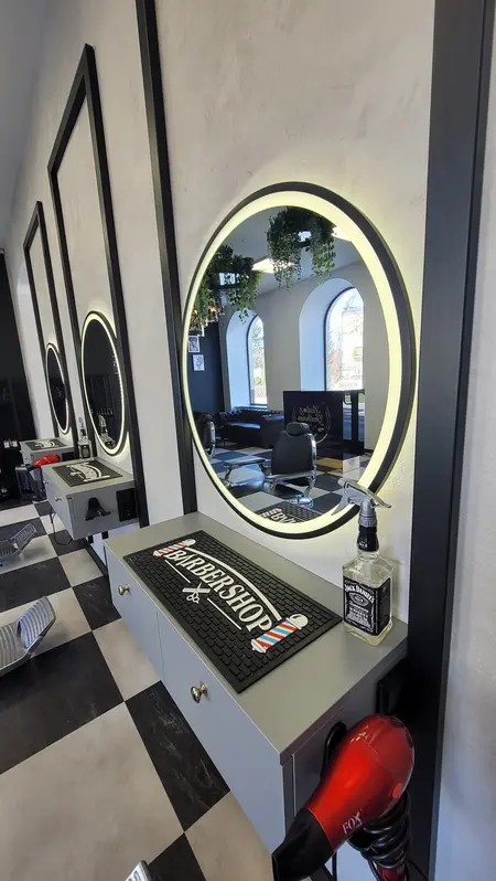 Wnętrze barber shopu z lustrami, roślinami i nowoczesnym wyposażeniem.