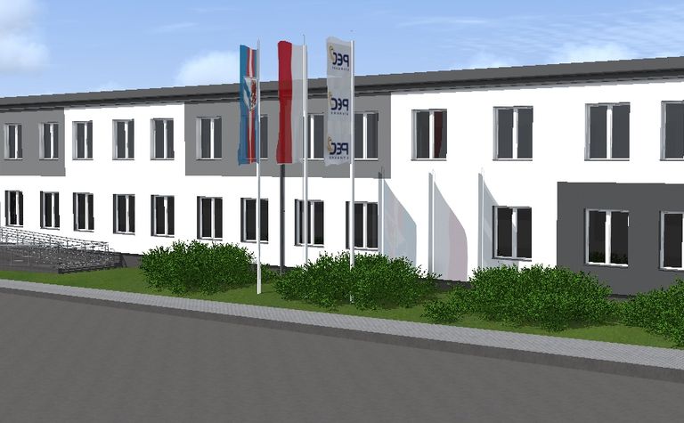Widok budynku z szaro-białą elewacją i zielonymi krzewami, styl industrialny i nowoczesny.
