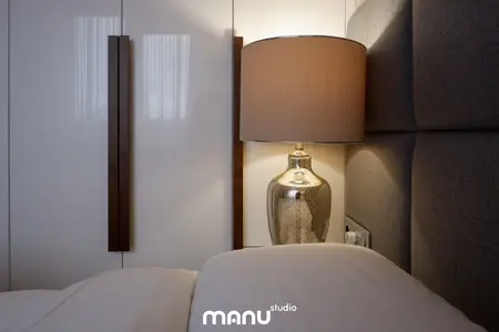 Sypialnia z tradycyjnym zagłówkiem i lampą w eleganckim stylu.