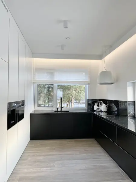 Nowoczesna kuchnia z białymi meblami i czarnym blatem, współczesny design.