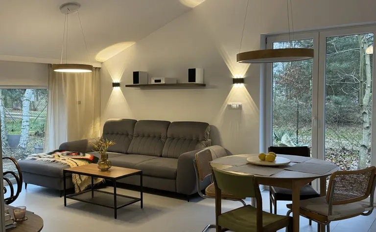 Wnętrze salonu w stylu boho, minimalistycznym i rustykalnym z szarym narożnikiem.
