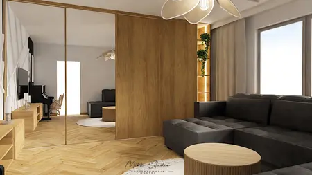 Nowoczesne wnętrze salonu z szarym narożnikiem, drewnianą podłogą i roślinnością.