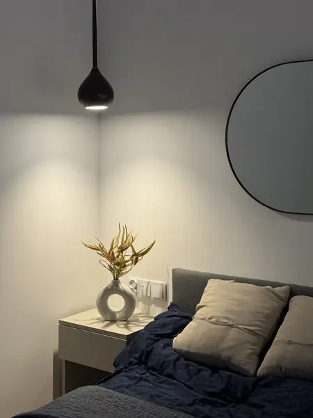 Wnętrze sypialni w stylu boho, minimalistycznym i rustykalnym z szarym łóżkiem i dekoracyjną lampą.