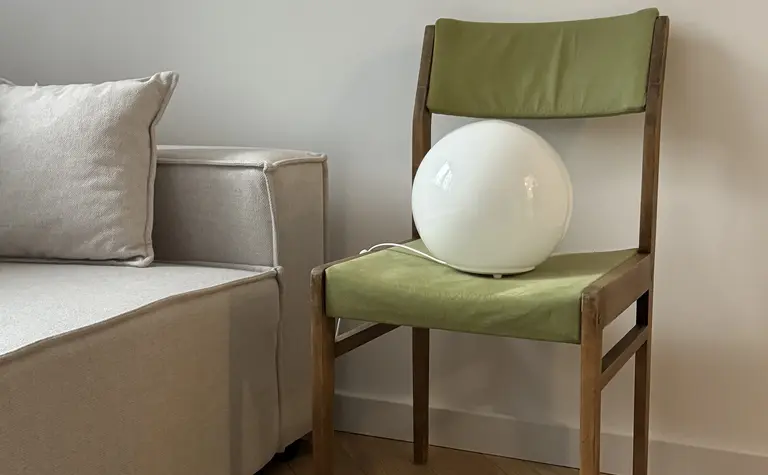 Pokój w stylu boho z minimalistycznym fotelem i rustykalnym oświetleniem.
