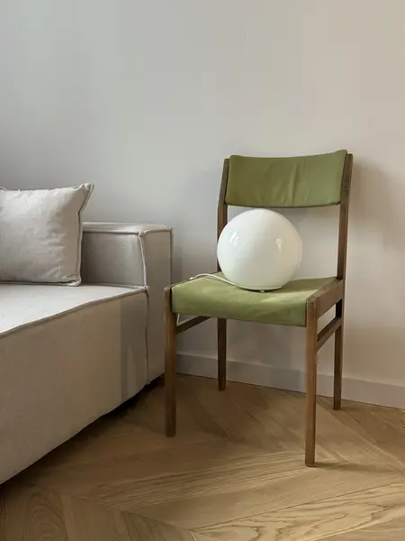 Pokój w stylu boho z minimalistycznym fotelem i rustykalnym oświetleniem.