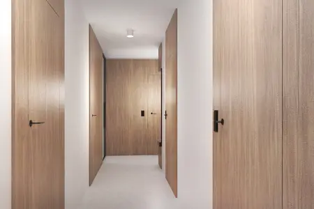 Korytarz z minimalistycznym designem, drewniane drzwi i jasne ściany