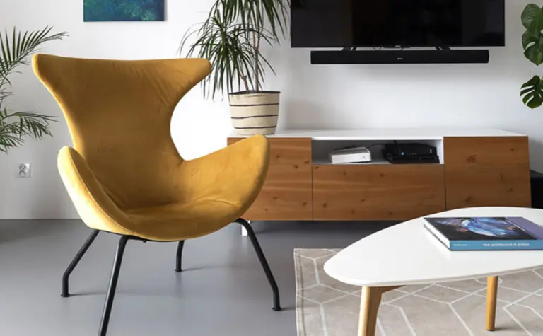 Wnętrze minimalistycznego salonu z żółtym fotelem, telewizorem i roślinami