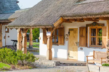 Zewnętrzny widok rustykalnego domu z drewnianymi elementami i strzechą, styl boho, eklektyczny, minimalistyczny.