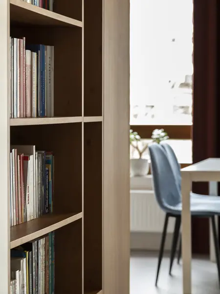 Minimalistyczne wnętrze z regałem na książki i niebieskimi krzesłami