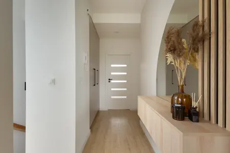 Przedpokój w stylu japandi z drewnianymi detalami i minimalistycznym wystrojem.