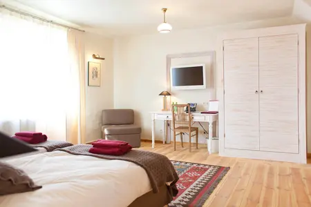 Wnętrze pokoju z elementami boho i minimalistycznymi, z biurkiem i dużym łóżkiem.