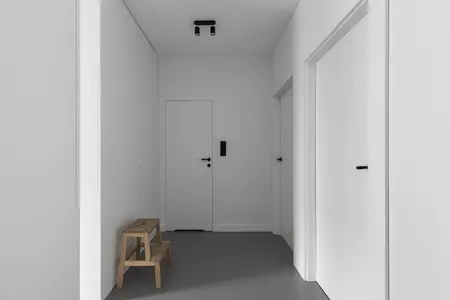 Przedpokój z minimalistycznym wystrojem, białe ściany i drewniana ławka.