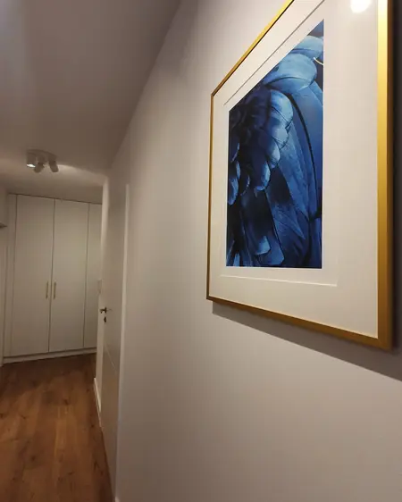 Korytarz z niebieskim obrazem i białymi meblami, styl skandynawski.