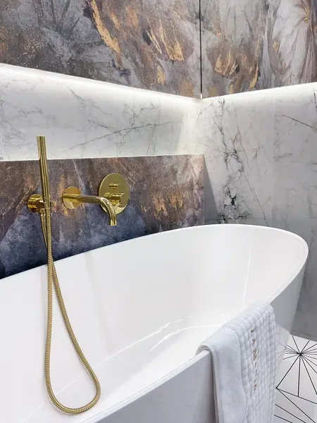 Nowoczesna łazienka z wanną, marmurowymi płytkami i złotymi detalami, styl glamour, japandi, minimalistyczny.