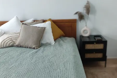 Sypialnia w stylu boho i japandi z zielonym kocem i poduszkami.