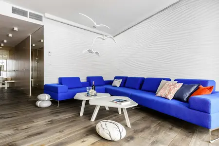Wnętrze salonu w stylu skandynawskim z niebieską sofą i białym stolikiem.