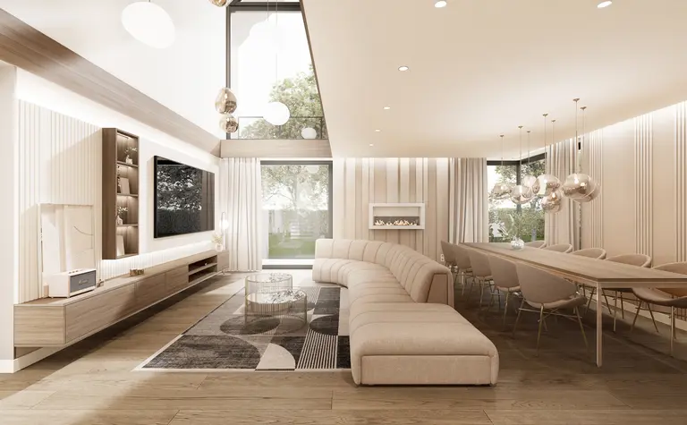 Elegancki salon z dużą, beżową sofą, nowoczesnym kominkiem oraz stołem jadalnianym z designerskimi lampami. Wnętrze o jasnych kolorach i panoramicznym oknie z widokiem na ogród.