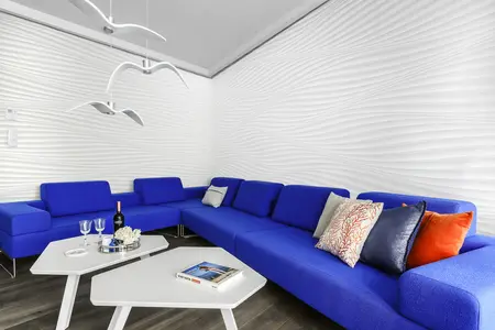Nowoczesny salon w stylu skandynawskim z niebieską sofą i białą ścianą.