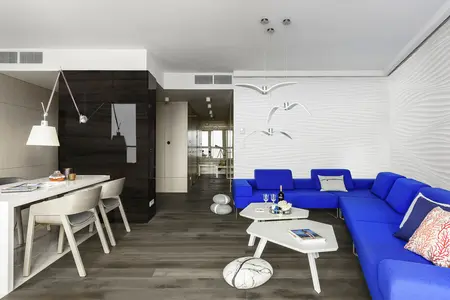 Wnętrze salonu w stylu skandynawskim z niebieską sofą i nowoczesnymi lampami.
