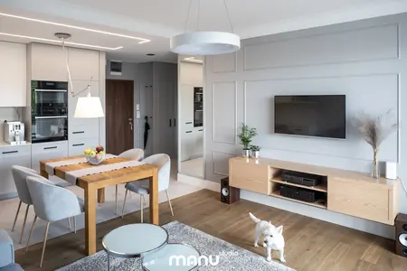Nowoczesne wnętrze z drewnianym stołem, szarymi meblami, elementami art deco, quiet luxury i tradycyjnymi akcentami.