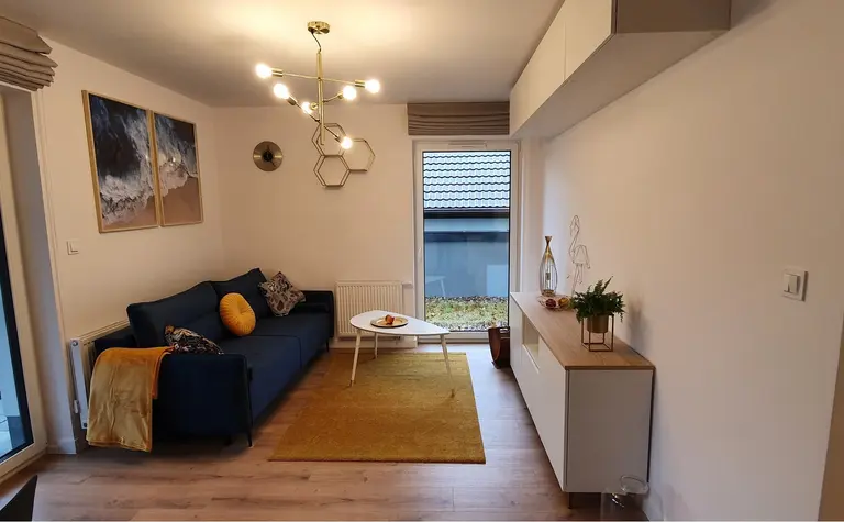 Nowoczesny salon w stylu skandynawskim z niebieską kanapą i białymi meblami.