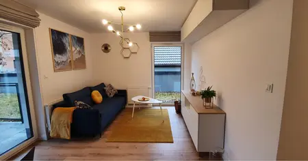 Nowoczesny salon w stylu skandynawskim z niebieską kanapą i białymi meblami.