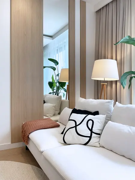 Wnętrze salonu w stylu glamour, japandi i minimalistycznym, z białą sofą i roślinami.