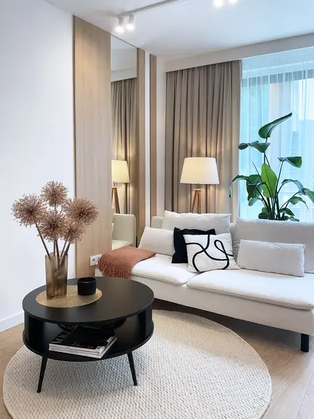 Nowoczesne wnętrze salonu z elementami glamour i japandi, biała sofa, czarny stolik.