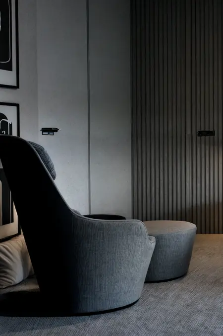Minimalistyczny salon z szarym fotelem i nowoczesnym akcentem.