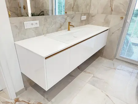 Nowoczesna łazienka z białą umywalką i złotymi detalami w stylu glamour.