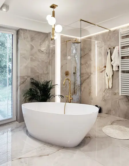 Nowoczesna łazienka glamour z białą wanną i złotymi detalami.