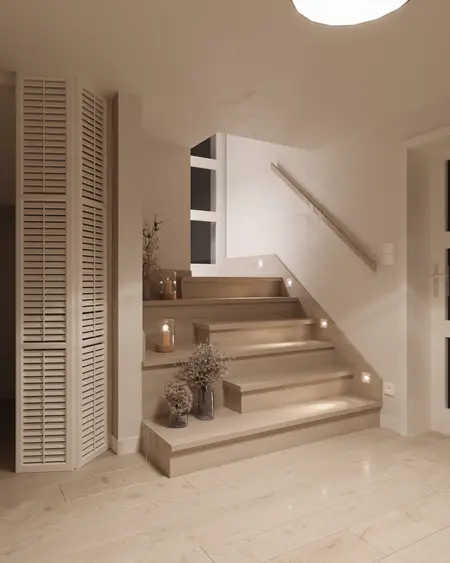 Minimalistyczna klatka schodowa z drewnianymi schodami i dekoracjami.