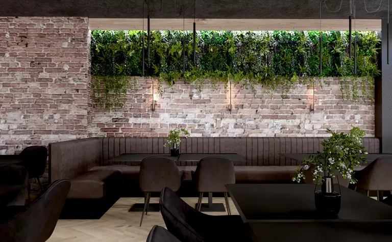 Restauracja z ceglaną ścianą, ciemnymi meblami i roślinnością, styl industrialny.
