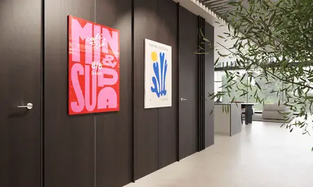 Wnętrze korytarza z minimalistycznym designem, nowoczesnymi plakatami i zielonymi roślinami.