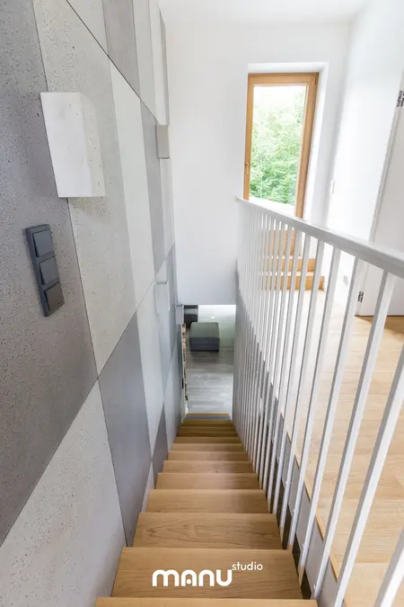 Wnętrze schodów z betonową ścianą i drewnianymi akcentami w stylu industrialnym i skandynawskim.