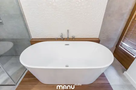 Wnętrze łazienki z białą wanną, drewnianymi detalami, w stylu industrialnym, minimalistycznym i skandynawskim.