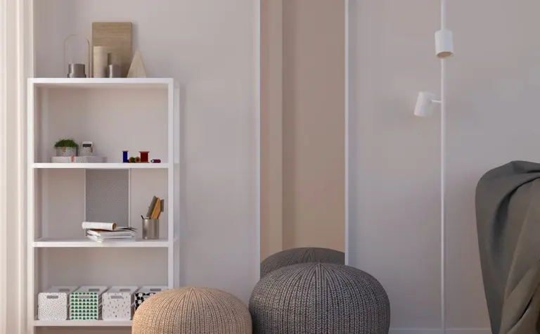 Minimalistyczny pokój z białą półką, szarymi pufami i dużym lustrem.