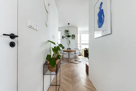 Wnętrze przedpokoju w stylu japandi z roślinami i drewnem.