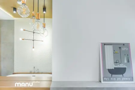Nowoczesna łazienka z wanną, industrialnym oświetleniem i minimalistycznym wnętrzem.