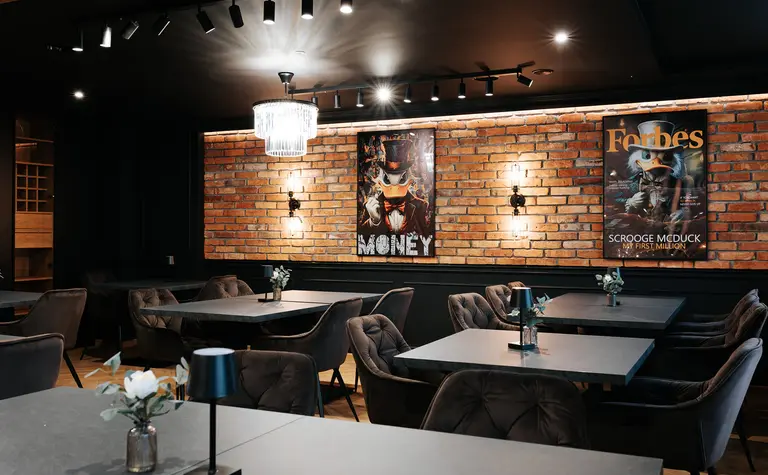 Wnętrze lokalu z ceglaną ścianą i nowoczesnymi meblami w stylu industrialnym.