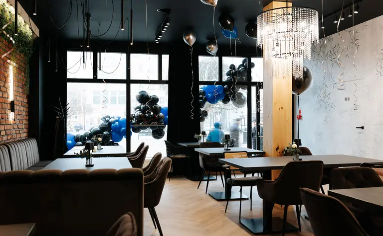 Wnętrze restauracji z industrialnym stylem, brązowe meble, czarne akcenty, eleganckie oświetlenie.