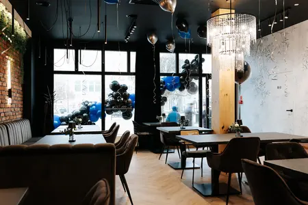 Wnętrze restauracji z industrialnym stylem, brązowe meble, czarne akcenty, eleganckie oświetlenie.