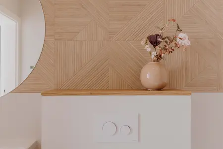 Wnętrze łazienki z drewnianą ścianą i wazonem w stylu skandynawskim.