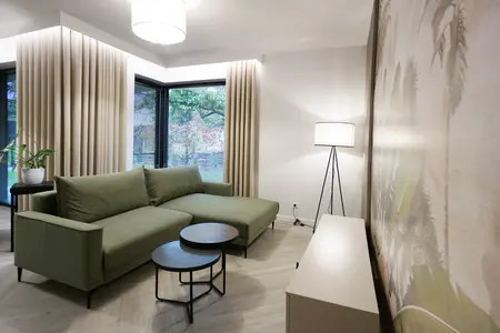 Wnętrze salonu w stylu boho i współczesnym z zieloną sofą.