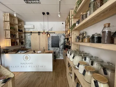 Wnętrze sklepu bez plastiku z drewnianymi półkami i słoikami na produkty sypkie, styl boho.