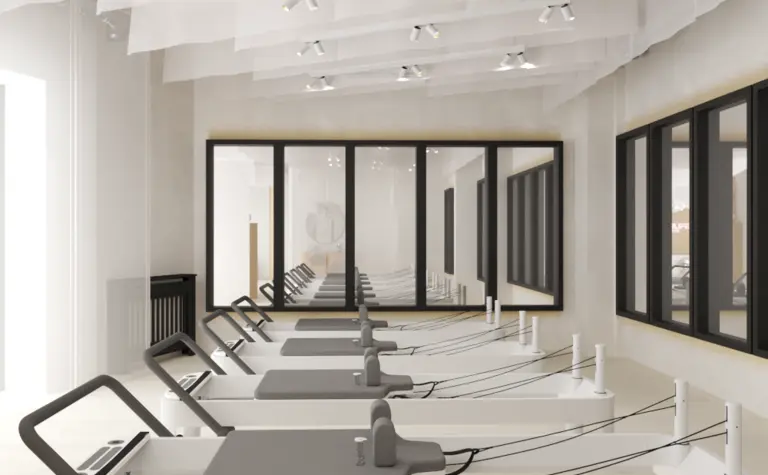 Nowoczesna sala do pilatesu w stylu soft minimalizm z białymi reformerami.