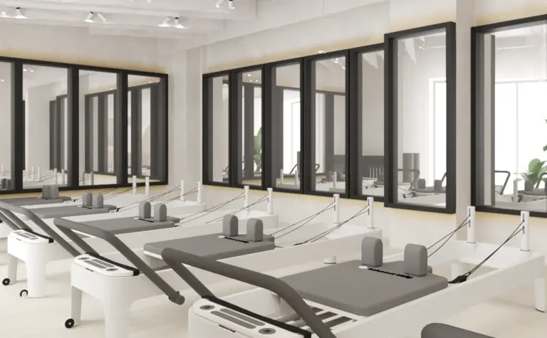 Studio pilates z białymi maszynami i dużymi oknami, soft minimalizm